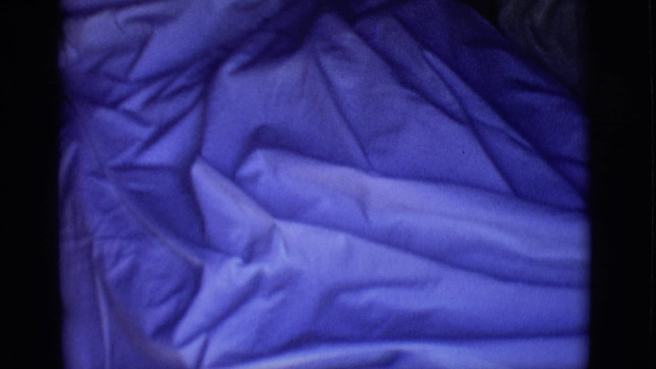 Close view of wrinkled blue plastic filling most of the dark frame.