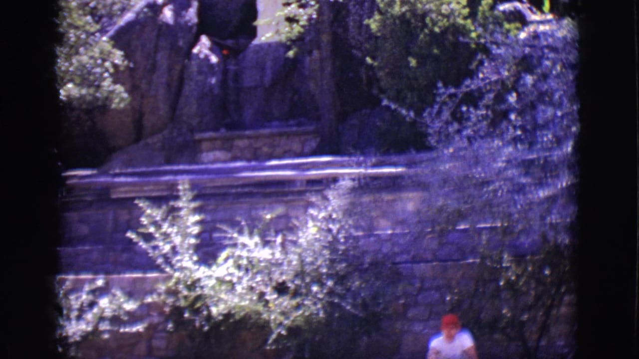 Stone wall and trees with a small person in a red cap near the lower edge.