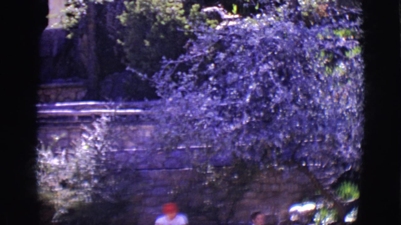 Trees and stone wall with two small figures partly visible near the bottom.