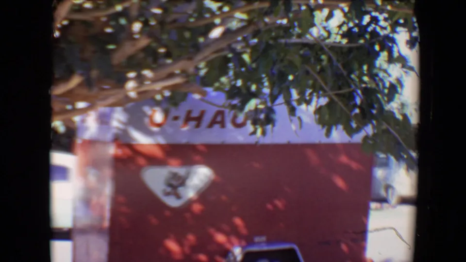 The final frame centers on the red-and-white U-Haul trailer in Evansville, with tree leaves and dappled shadows crossing the branded side panel.