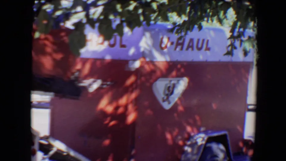 8mm frame from Evansville showing a red-and-white U-Haul trailer partly obscured by shade and film-frame borders.