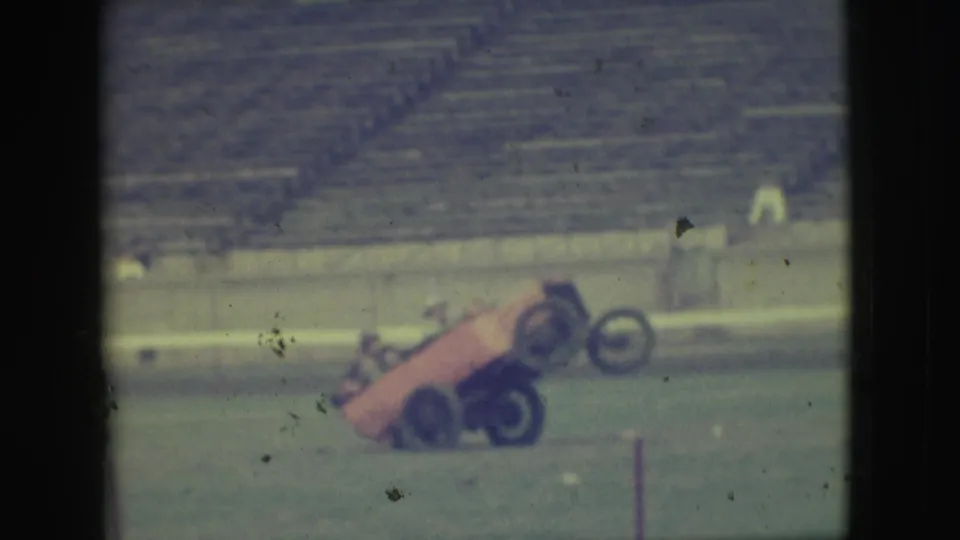 The Denver home-movie frame shows the experimental car still reared back during the stunt, with bleachers in the background.