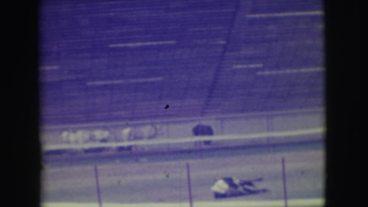 Distant racetrack view with a horse and rider down near the rail.