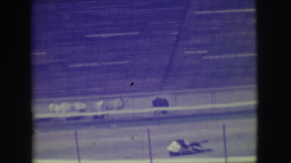 1949 Denver racetrack footage shows a distant horse and rider down near the inside rail beneath stadium bleachers.