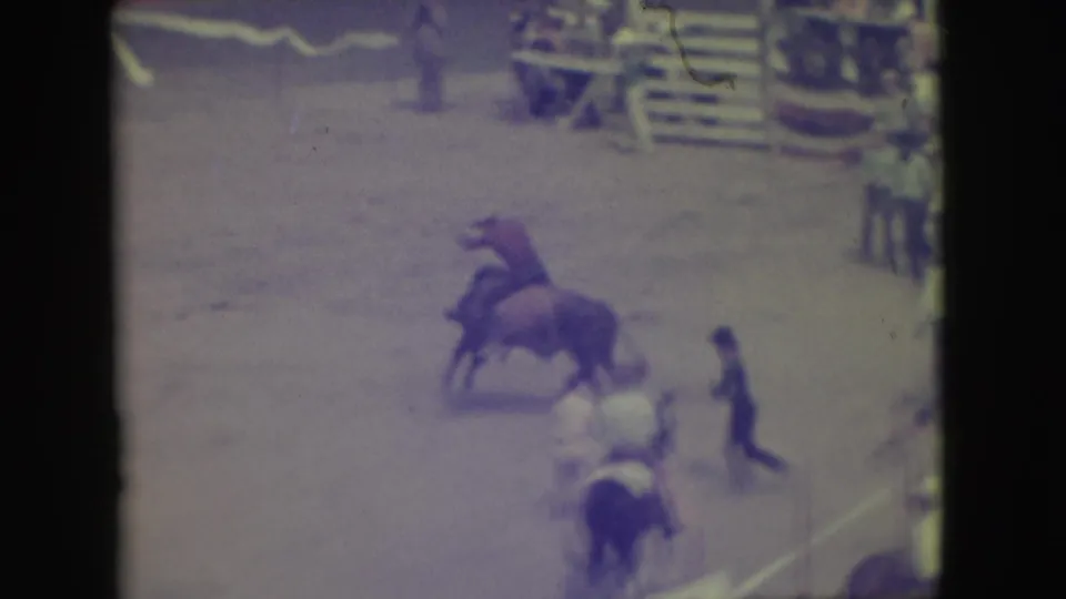 1949 Denver rodeo frame showing a cowboy on a bucking bull, with arena assistants and horseback figures nearby.