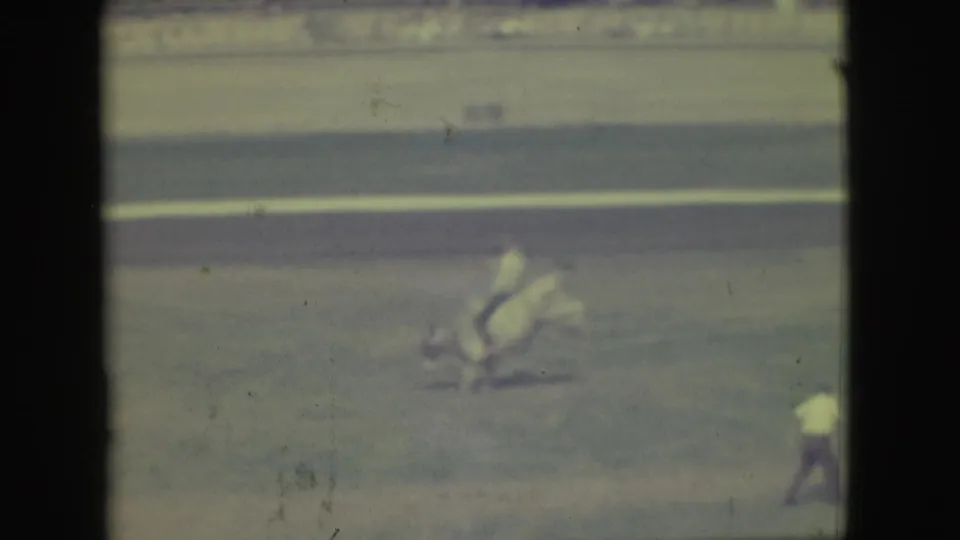 In 1949 Denver footage, a horse and rider cross a distant dirt arena while a crowd watches from behind fencing.