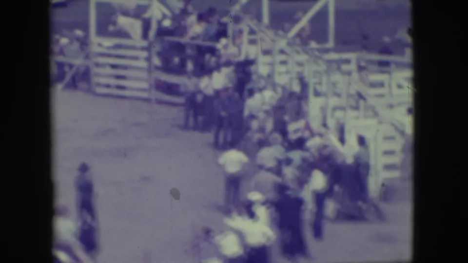 A small crowd stands beside fairground railings and steps in the Denver arena area, with figures visible in soft 8mm focus.