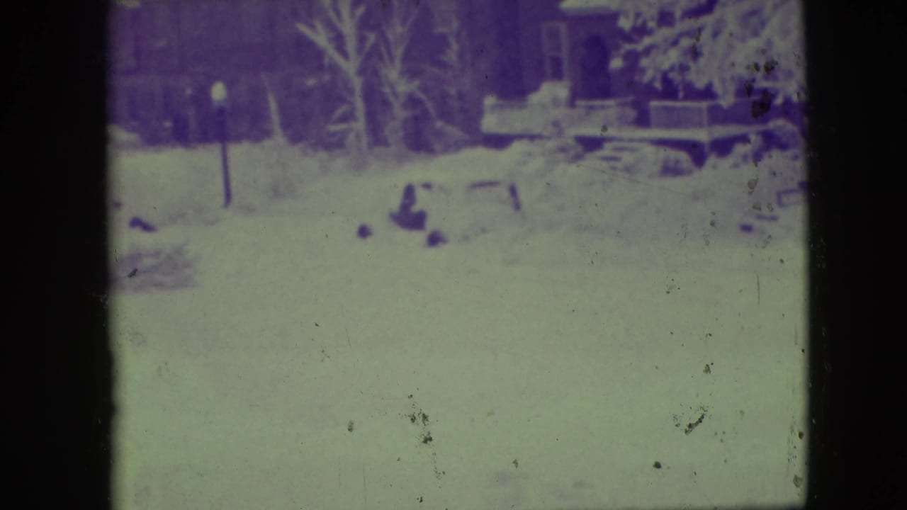 1945 Elmwood Park home-movie frame showing a snow-blanketed residential area with bare trees and heavy color shift.