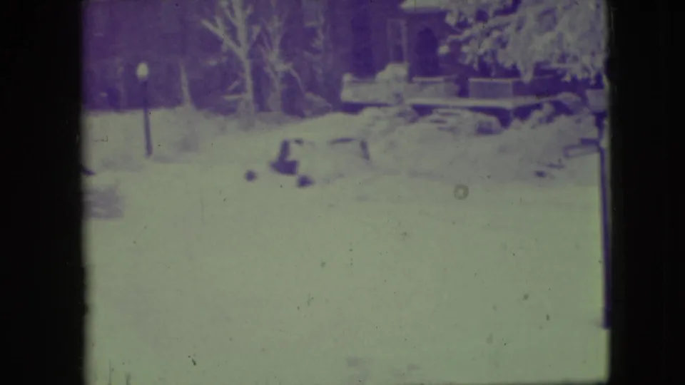 Elmwood Park winter frame from 1945 showing deep snow across a quiet residential street or yard with house fronts in the background.
