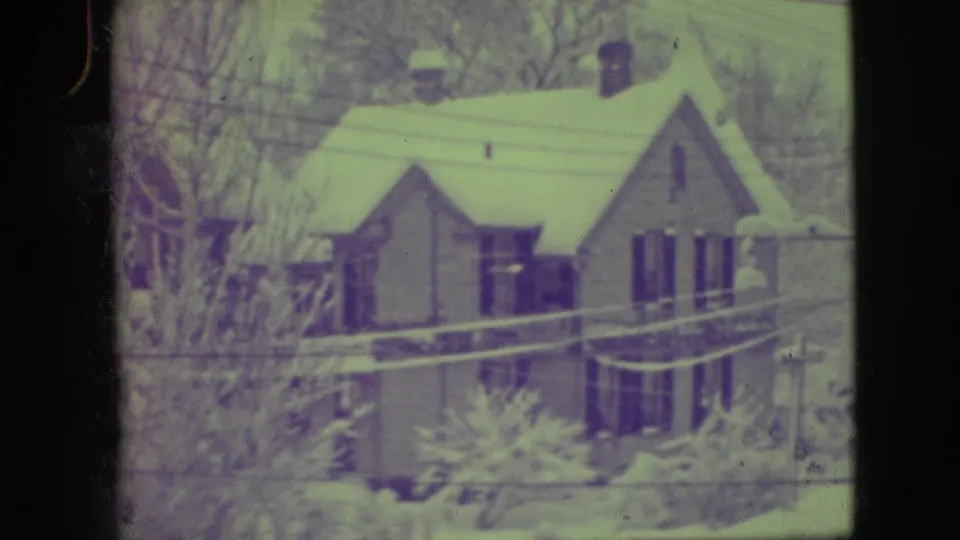 1945 Elmwood Park frame showing a lighter house with a steep snow-covered roof, bare trees, and utility lines crossing the view.