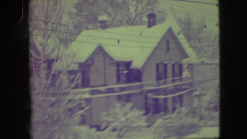 Elmwood Park winter frame from 1945 showing a snow-covered sloped-roof house, bare trees, and crossing utility lines.