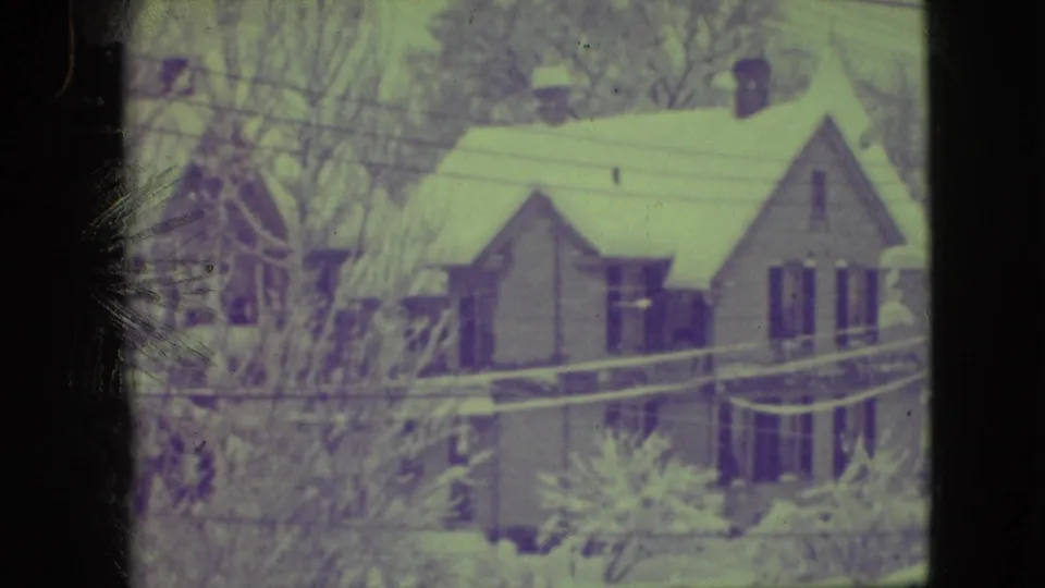 1945 8mm view of a snow-covered Elmwood Park house framed by winter trees and overhead lines.