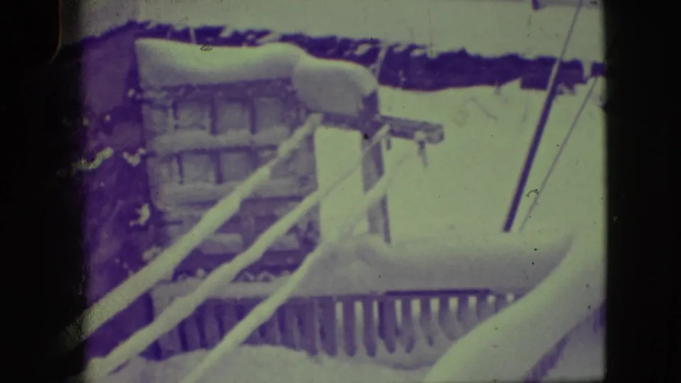 Closer 1945 Elmwood Park view showing snow along a porch railing, brick foundation, and winter accumulation.