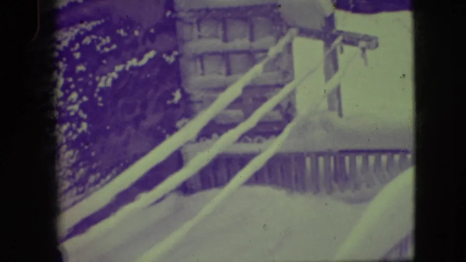 Snow on a porch railing and nearby house exterior in 1945 Elmwood Park home-movie footage.