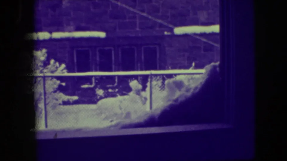 1945 Elmwood Park frame showing snow outside a window, with a fence, utility wires, and a masonry residential building.