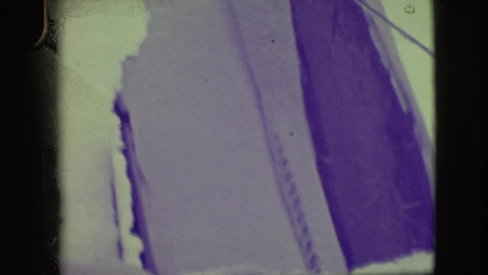 1945 Elmwood Park home-movie frame with a close, partially obscured window view of snow and dark vertical exterior shapes.