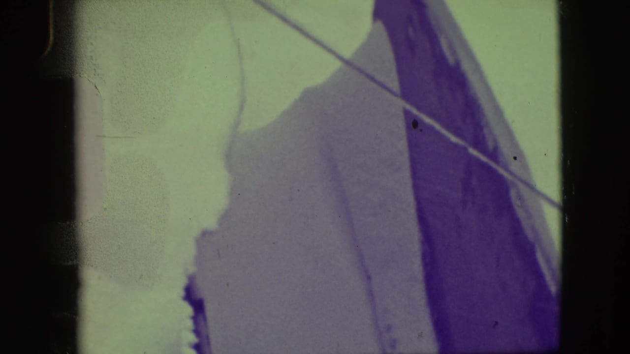 Close view of a large sail with angled rigging lines and dark film-frame edges.