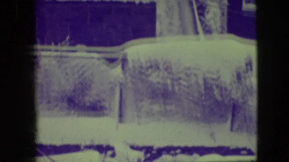 Final 8mm frame appears to show a snowy outdoor yard area with a wall or fence, affected by strong purple-green color shift.