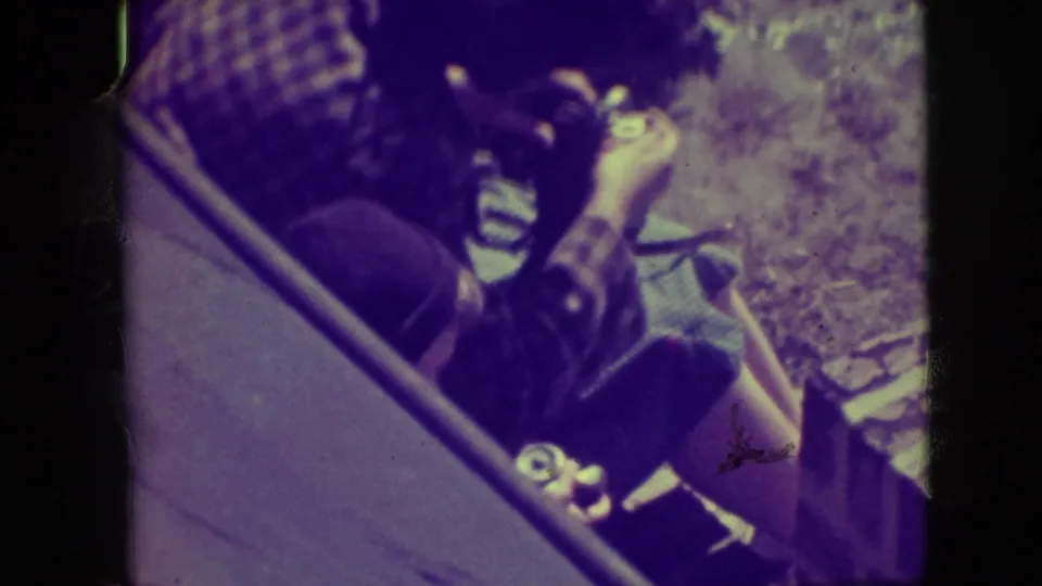 A man in a plaid shirt appears to adjust a small camera outdoors in Elmwood Park, Illinois, in 1945.