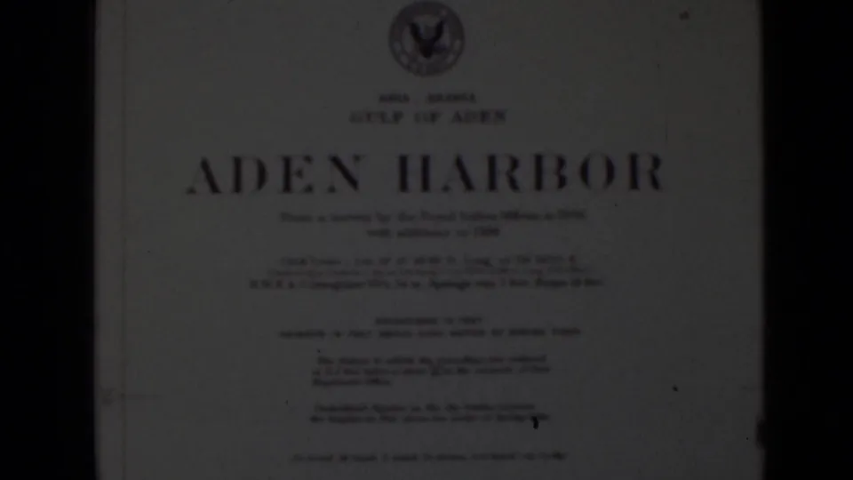 Soft 8mm frame of a white Aden Harbor title card with large blue lettering, smaller chart text, and a crest-like emblem above.