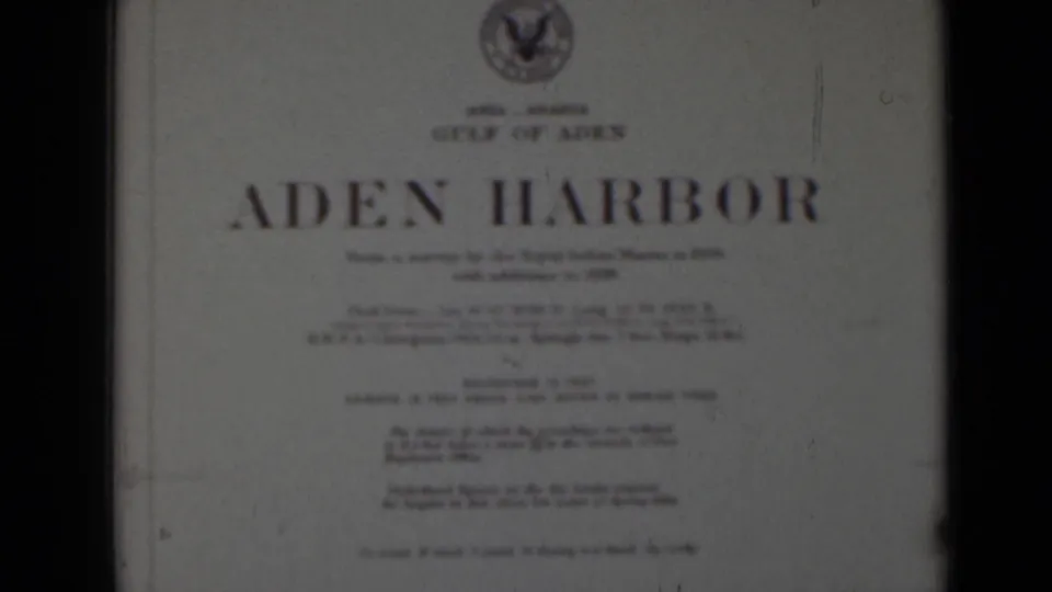 Soft-focus 8mm view of the Aden Harbor title card, showing the top crest, large title, and smaller printed survey details.