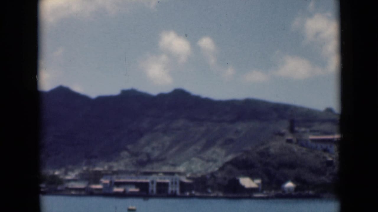 1940s 8mm frame identified in metadata as Aden, Yemen, showing shoreline buildings across water beneath steep mountains.