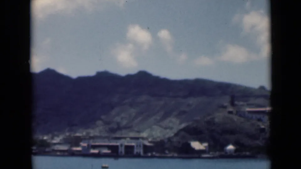 1940s 8mm frame identified in metadata as Aden, Yemen, showing shoreline buildings across water beneath steep mountains.