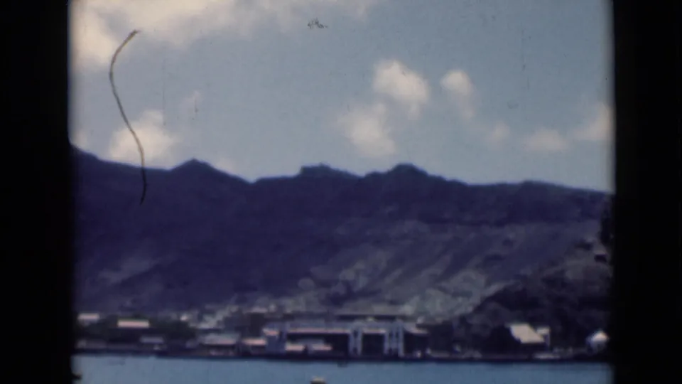 Metadata-identified Aden waterfront view with low shore structures, calm water, and steep hills under a pale sky.