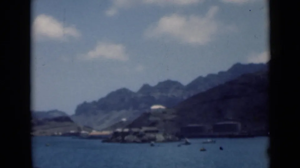 Final 8mm frame of the coastal view, identified in metadata as Aden, Yemen, with water, boats, shoreline structures, and mountains.