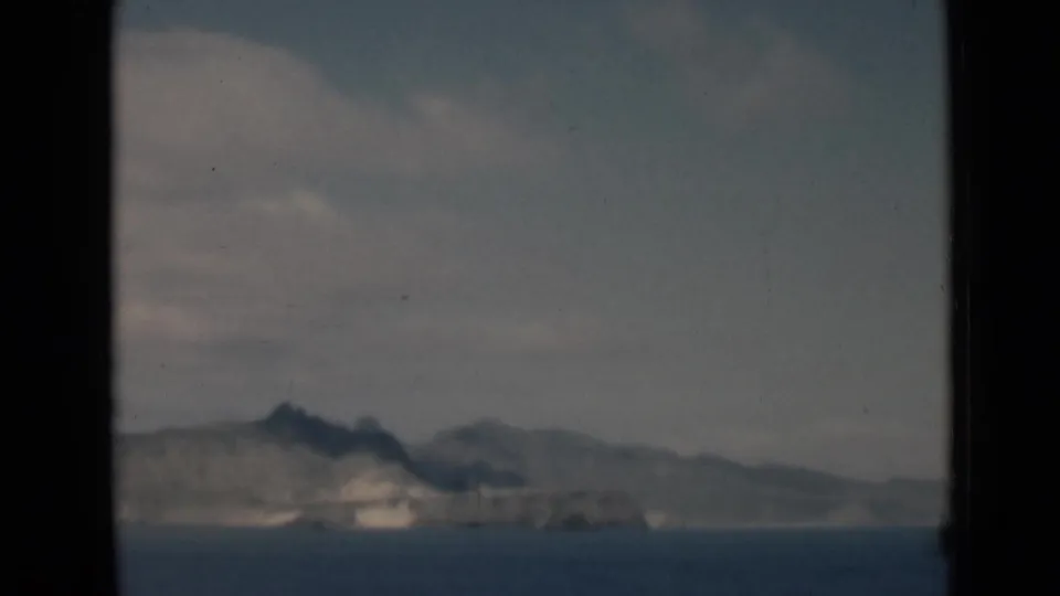 Soft 8mm frame of a hazy rocky coast or island across open water, supported by metadata as Aden, Yemen, in 1946.