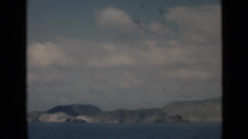 1940s 8mm home-movie frame of a hazy coastal mountain horizon and blue sea, associated by metadata with Aden, Yemen.