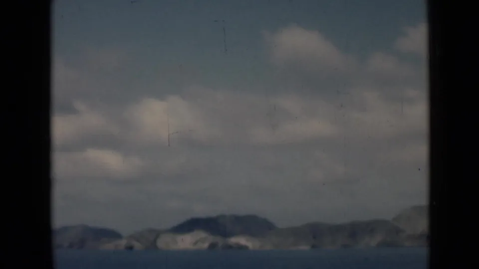 Soft 8mm travel view of sea, distant mountains, and clouded sky, visually consistent with the clip's 1946 archive metadata.