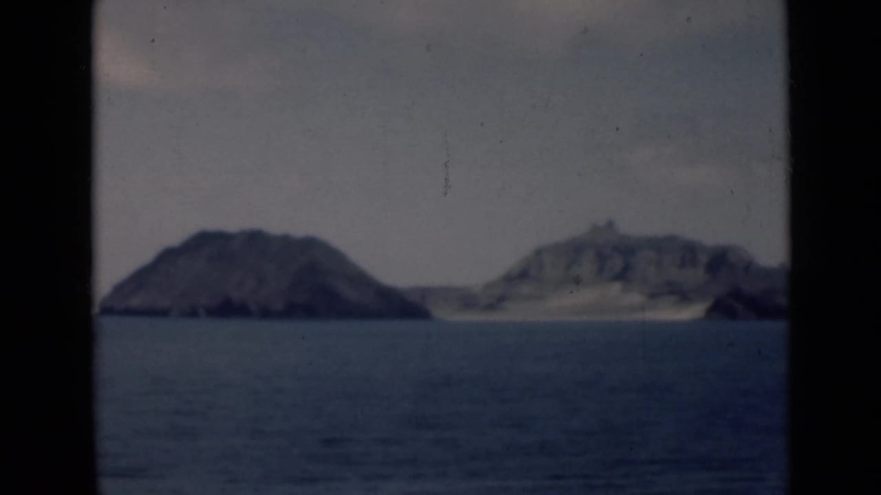 Rocky islands across calm water under a hazy sky.