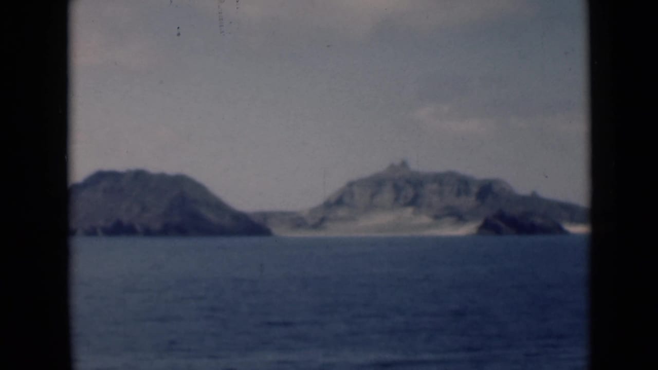Distant rocky islands framed by dark film borders.
