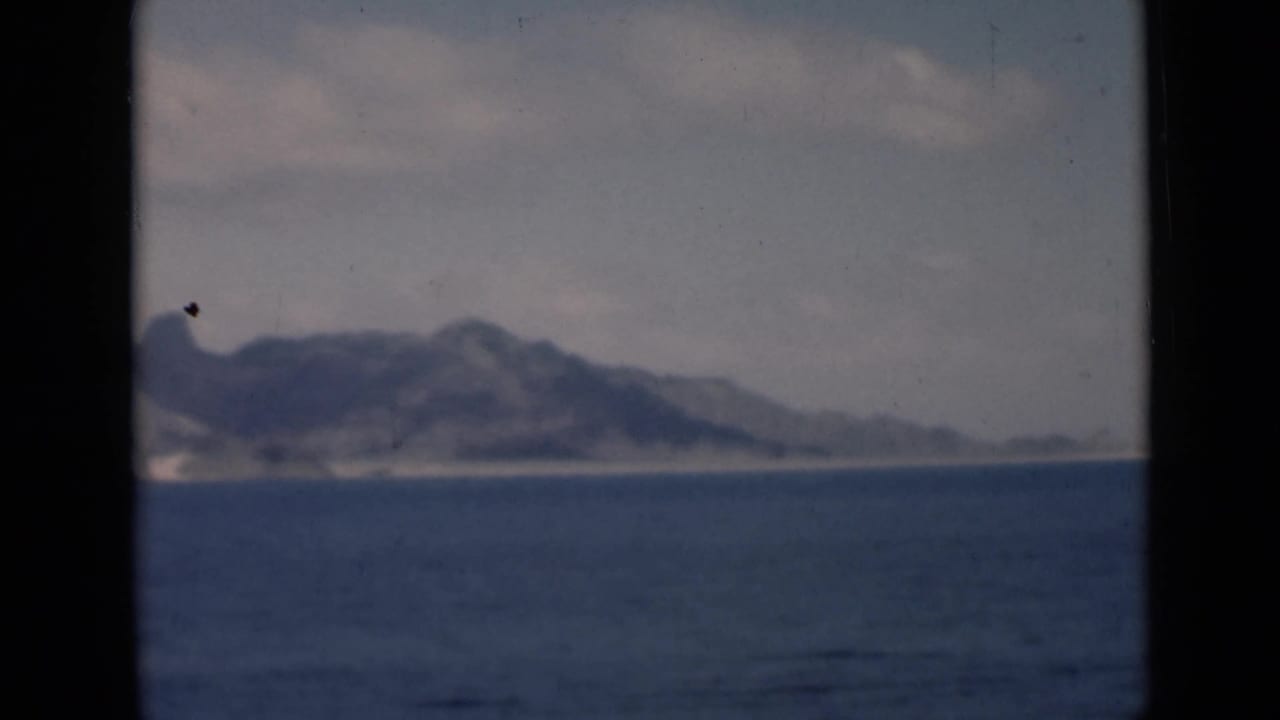 Hazy coastal mountains beyond open water with dark vertical frame edges.