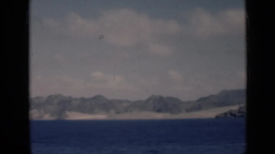 Aden/Yemen-labeled 1940s 8mm frame showing a distant mountainous shoreline across calm water, with dark film borders.