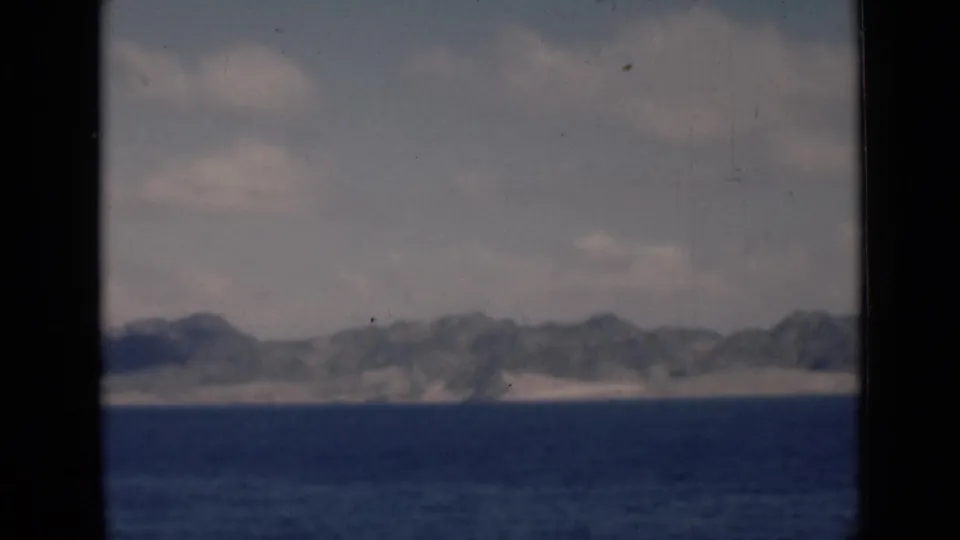 Final frame shows a hazy mountainous coast across the water, with visible grain and dark small-gauge film borders.