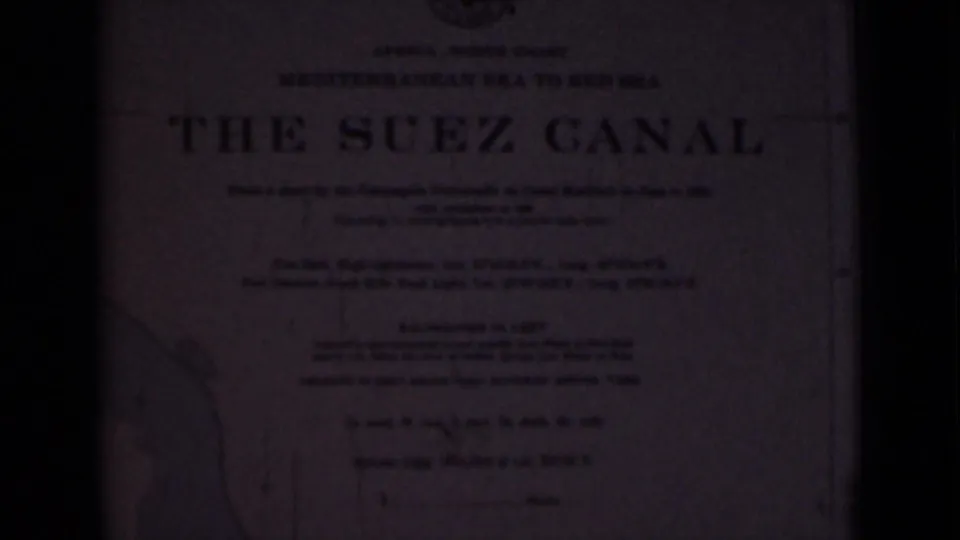 Printed title-card material headed The Suez Canal, photographed in dim exposure with map-like linework near the edge.