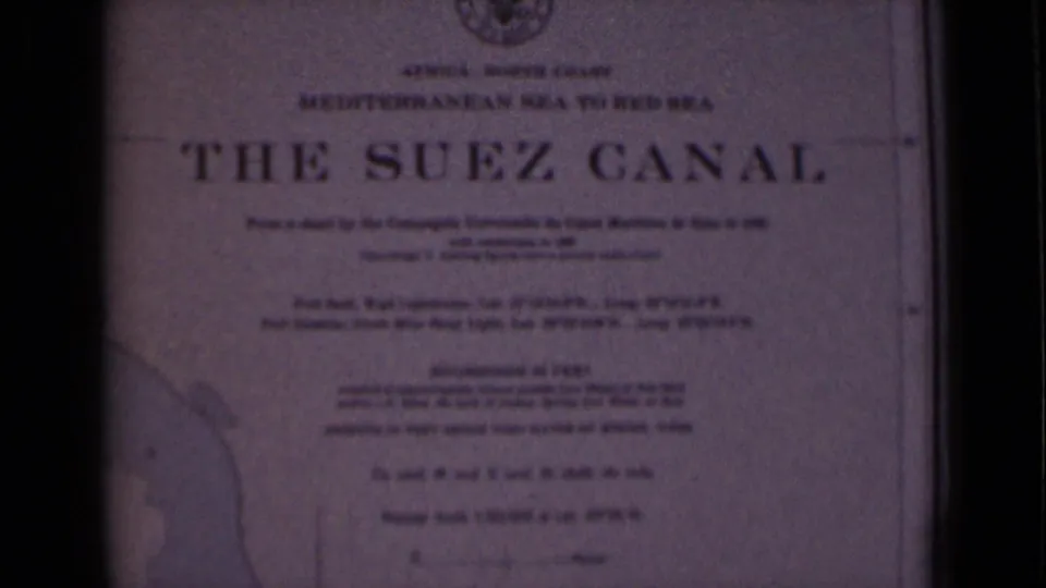 A closer 8mm view of a printed The Suez Canal title card, with smaller text below and visible film grain.