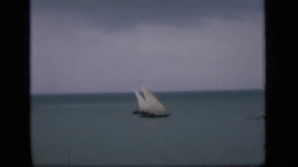 1946 Bombay coastal frame with a small sailboat in the distance on muted blue-green water.