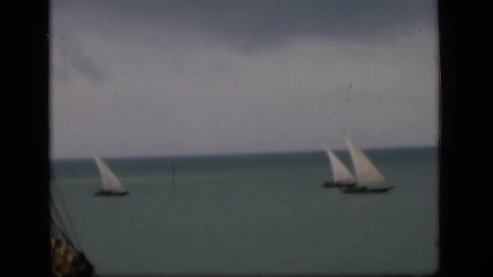 1946 Bombay home-movie view of separated sailboats on calm coastal water, with soft focus and visible film texture.