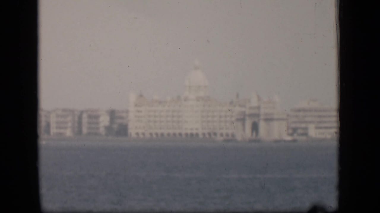 1946 Bombay home-movie frame showing the Taj Mahal Palace Hotel area across water through haze and soft focus.