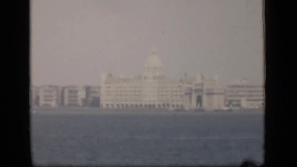 1946 Bombay home-movie frame showing the Taj Mahal Palace Hotel area across water through haze and soft focus.