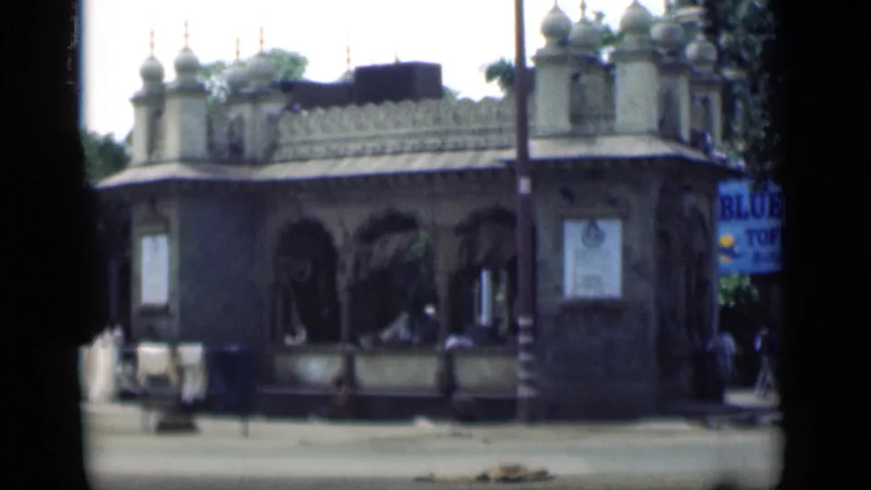 An ornate Bombay street facade with arched openings appears in the same 1946 home-movie sequence, with pedestrians along the sidewalk.