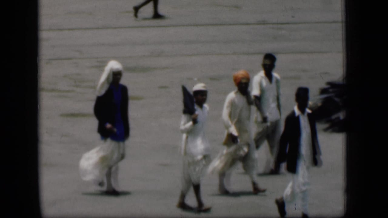 Group of people in traditional clothing walking across a paved area.