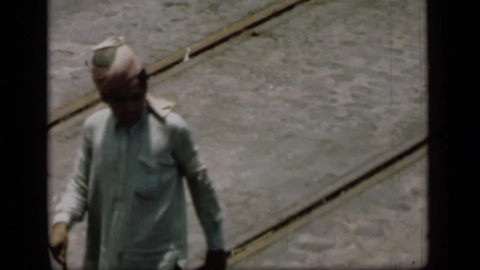 The 1946 Bombay street view shows a turbaned man in pale clothing continuing past tram tracks with a cane in hand.