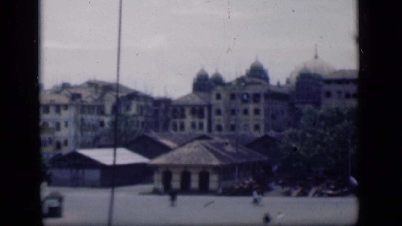 1946 Bombay view across an open plaza toward domed colonial-era buildings, with trees and distant pedestrians.