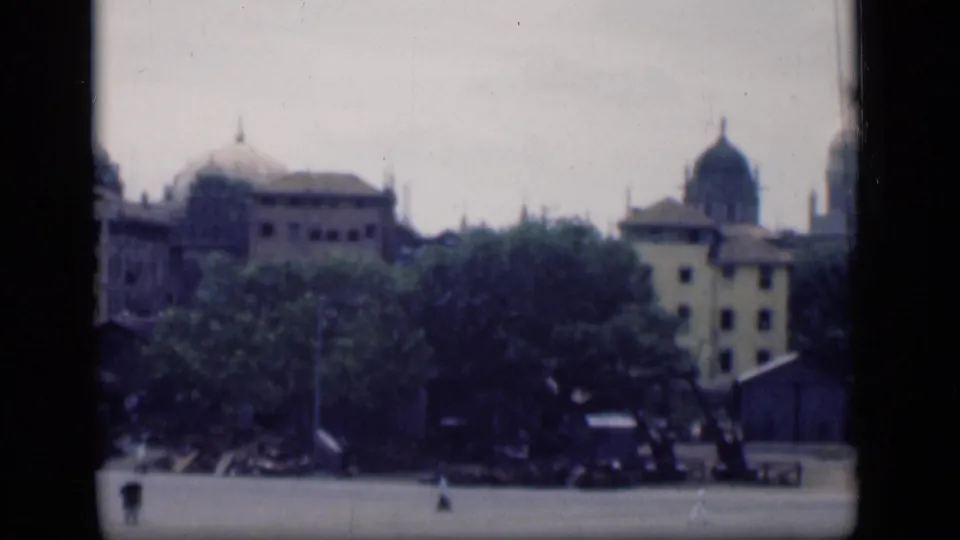 1946 Bombay view with trees across the foreground and domed urban buildings visible in soft 8mm color.
