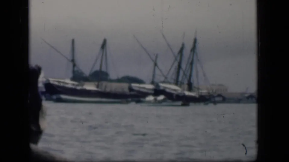 1946 Bombay harbor scene with moored mast boats across the water and a partially visible person at the left edge.