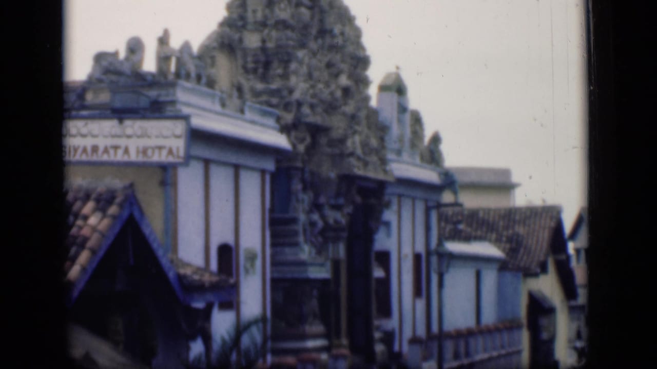 1946 Bombay 8mm frame showing an ornate temple tower above low buildings and a partially visible hotel sign.